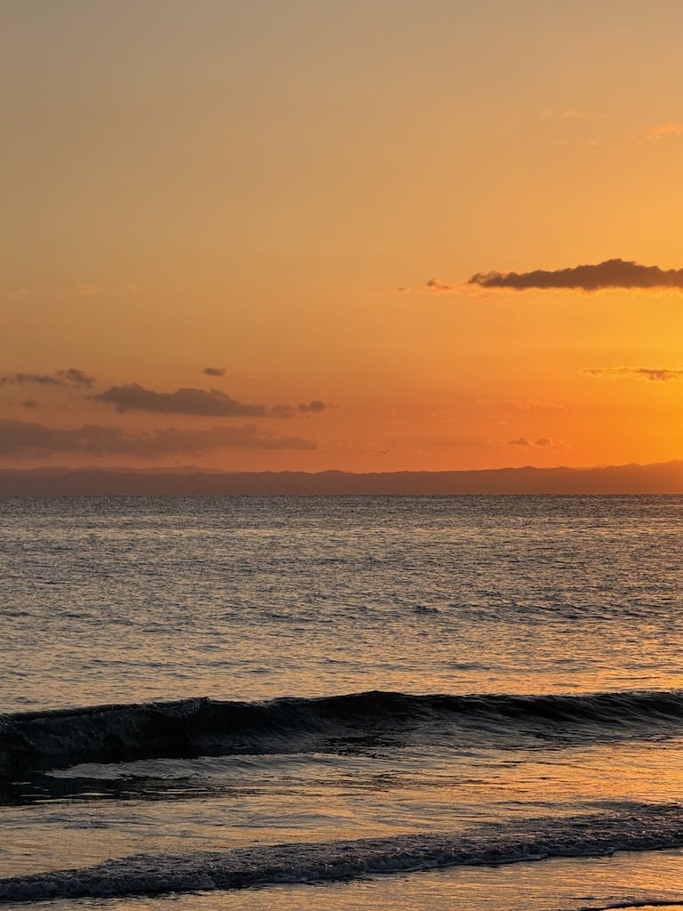 Captivating sunset over Kamakura beach, Japan, with glowing skies and calm ocean waves.